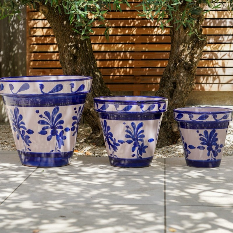 Drie Spaanse keramieken bloempotten in blauw-wit onder een olijfboom